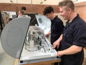 Students fitting aircraft equipment synthetic training rig